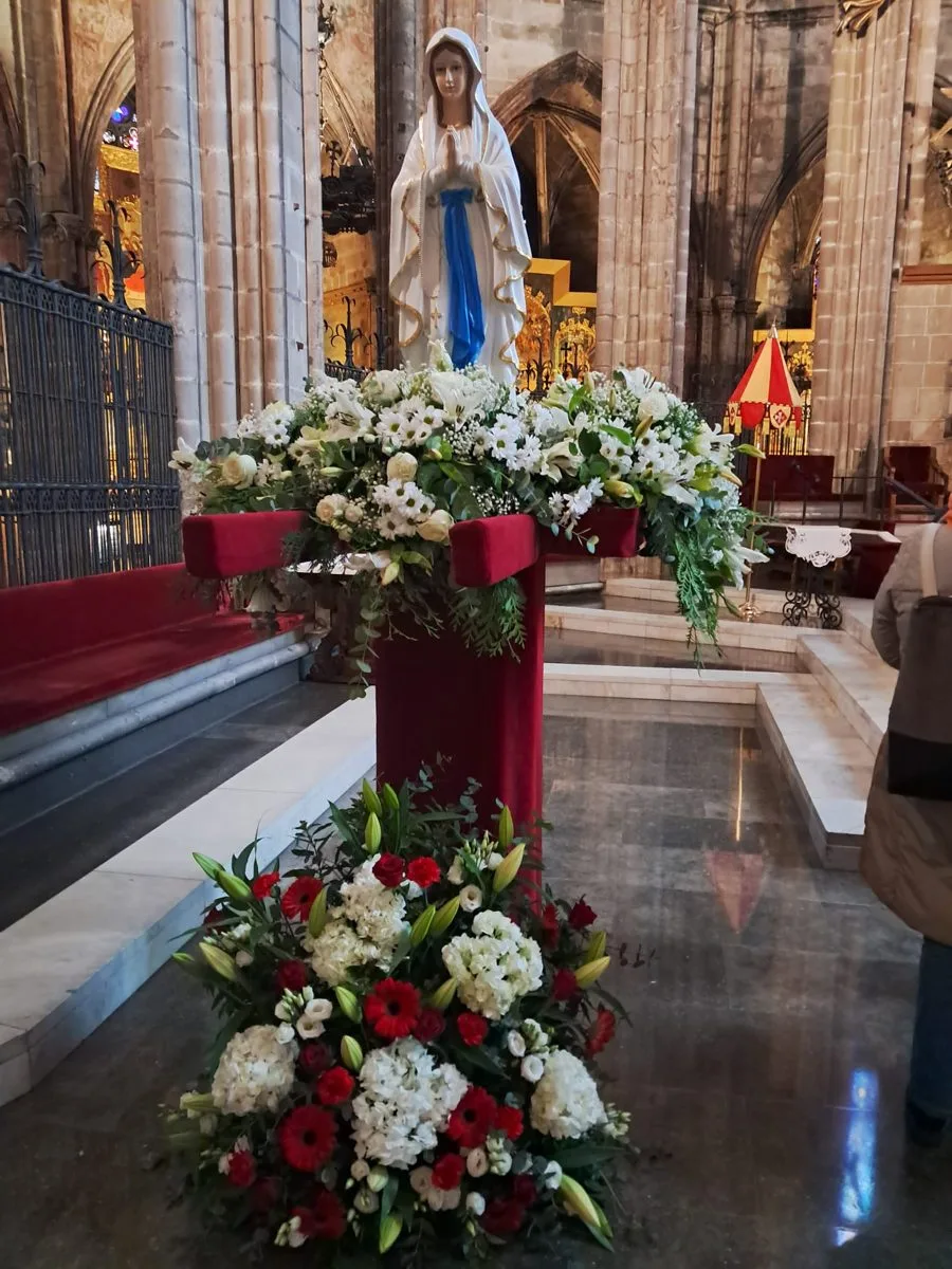 Imatge de la Mare de Déu de Lourdes envoltada de flors a la Catedral de Barcelona